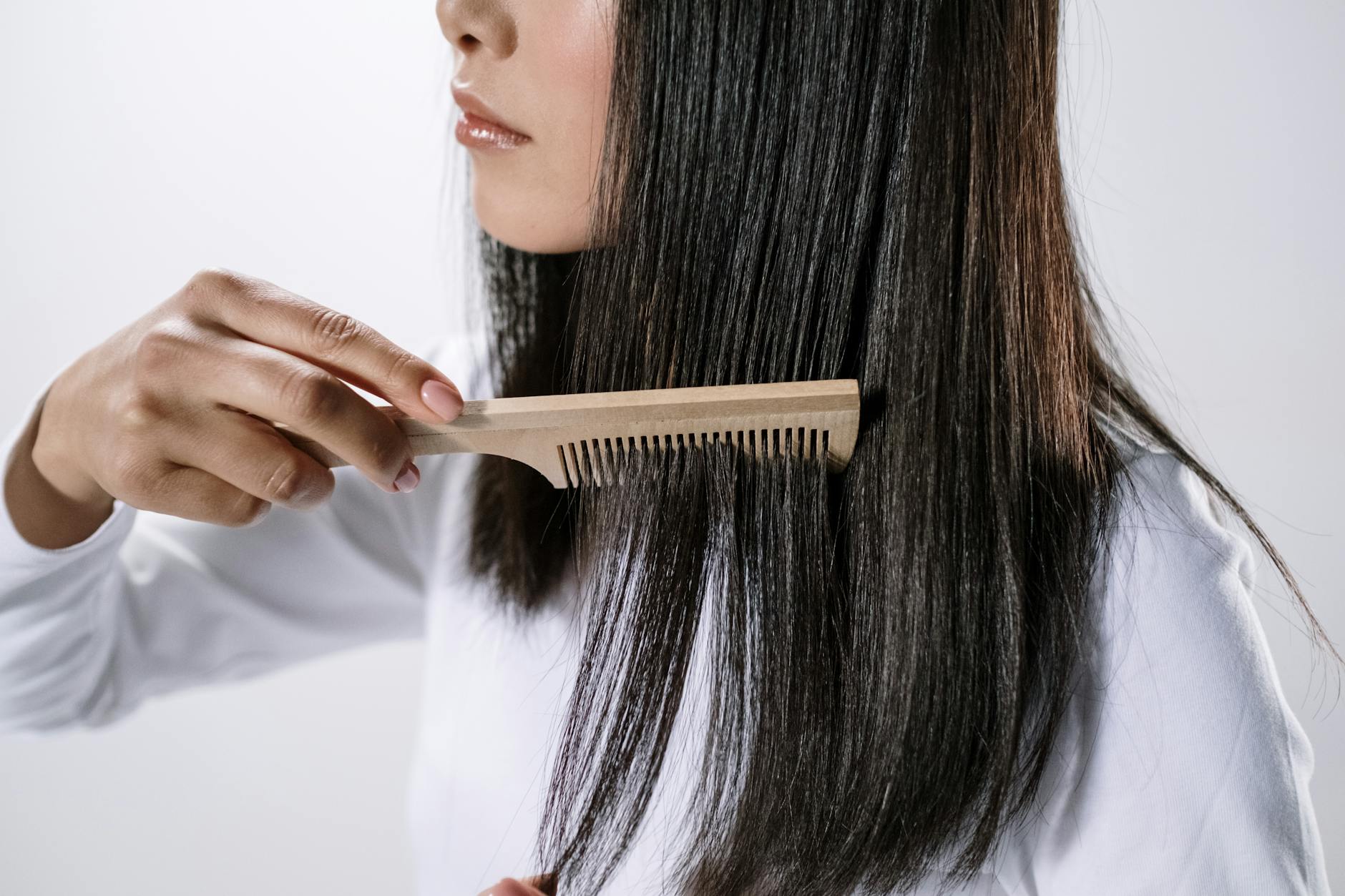 woman holding brown wooden hair comb